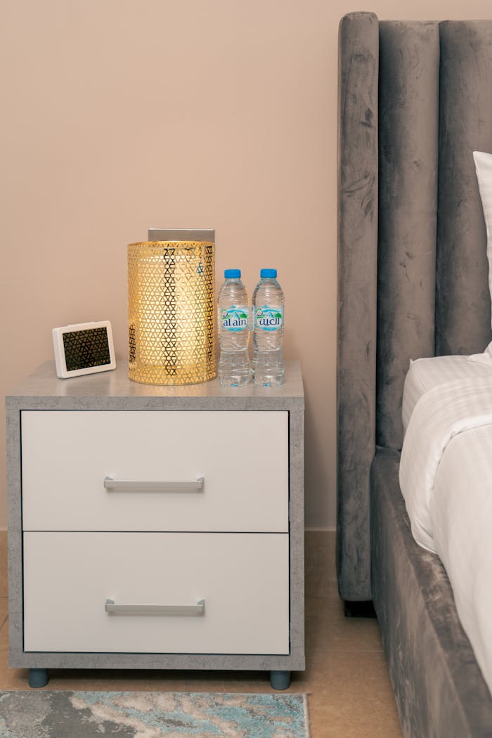 Stylish nightstand setup in a Dubai hotel room featuring a lamp, water bottles, and neat decor.